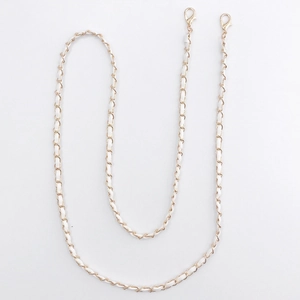 Detail of golden metal chain woven with white leather and lobster clasps for bags