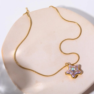 Dettaglio del ciondolo a forma di stella con smalto viola e strass rosa su catena dorata