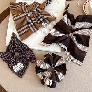 Close-up of brown striped and plaid fabric scrunchies with labels on a vintage book