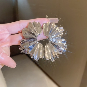 Macro shot of silver vintage-style earrings with irregular pleated flower texture
