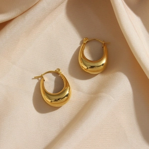 Macro shot of 18K gold plated hollow hoop earrings on champagne silk background
