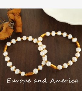 Detailed close-up of two natural freshwater pearl bracelets with gold-plated metal accents