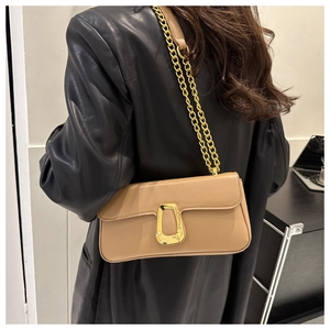 Detail view of beige leather shoulder bag with golden buckle and metal chain strap