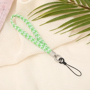 Handwoven green and white phone wrist strap with metal clasp on aesthetic mesh background