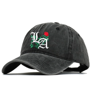 Detailed view of white Gothic LA embroidery and red rose on washed black baseball cap