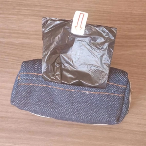 Detail of denim pet waste bag dispenser showing black plastic bag being pulled out