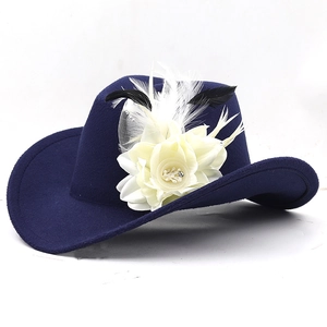 Detailed close-up of dark blue wool fedora with white fabric flower and feather ornaments