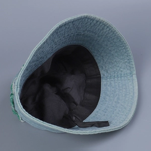 Detailed inner view of denim bucket hat featuring black lining and green letter embroidery