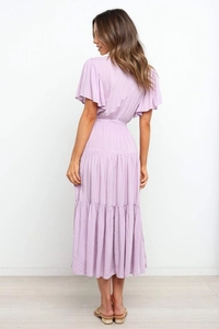 Vista trasera del vestido maxi lavanda con volantes y falda de capas con lazo alto