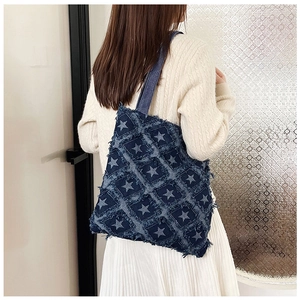 Close-up of dark blue denim tote bag with frayed star patch pattern and textured fabric