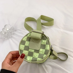 Cylindrical checkerboard crossbody bag with green wide shoulder strap and textured fabric