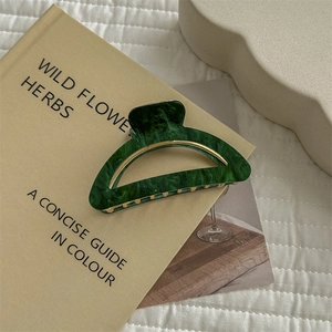 Detail of green marble hair claw clip with gold metal spring on an aesthetic book