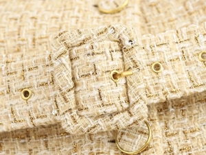 Detail of tweed vest fabric with gold-tone buckle and shimmering sequin texture