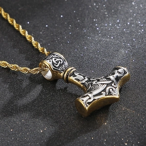 Macro shot of Viking Mjolnir pendant with Celtic patterns and golden twisted chain detail