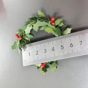 Christmas napkin ring with red berries and pine needles shown with ruler for size reference
