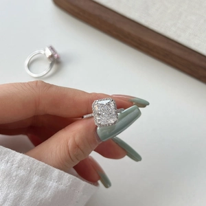 Macro shot of silver ring featuring radiant cut center stone with halo diamond setting