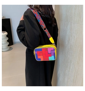 Detail of yellow crossbody bag with colorful geometric pattern and wide shoulder strap