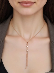 Detail of rose gold necklace with star charms and zircon tassels worn by a model