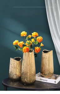 Close-up of golden electroplated ceramic vases with vertical stripes and wavy rims