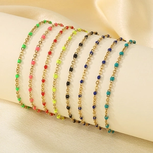 Colorful resin bead stainless steel anklets displayed on a beige cylinder prop