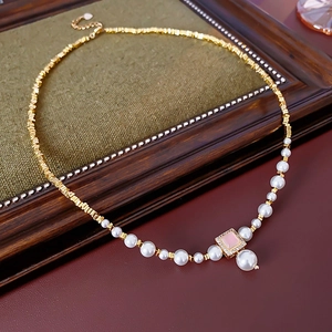 Close-up of 18k gold plated necklace with pearl and pink square gemstone on a frame