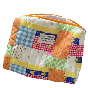 Quilted patchwork cosmetic bag with vibrant floral patterns and yellow zipper closure