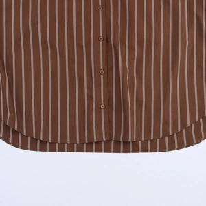 Detail of a brown striped cotton shirt showing curved hem and button placket