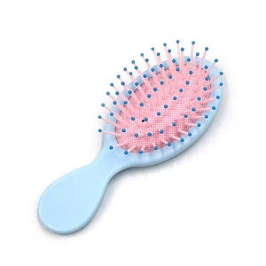 Detail of portable mini air cushion hairbrush with pink base and blue massage bristles