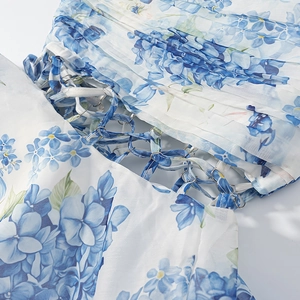 Detail of blue hydrangea floral print on pleated white fabric with metal ring and ribbon