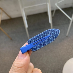 Close-up of a blue denim polka dot hair clip held by hand showing fine fabric detail