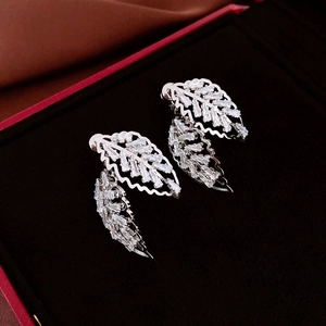 Gros plan de boucles d'oreilles feuilles en argent avec zircons sur velours noir élégant