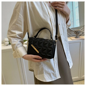 Close-up of black quilted shoulder bag with gold hardware and chain strap on a model