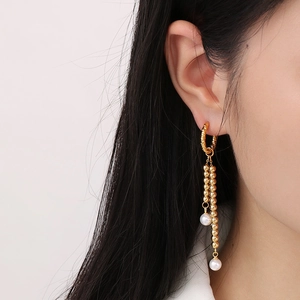 Close-up of golden tassel chain earrings with pearls on model for elegant drop effect