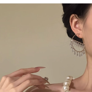 Macro shot of silver tassel earrings with trapezoidal cubic zirconia and pearl necklace