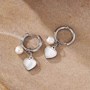 Detailed macro view of silver stainless steel heart shell and pearl drop earrings