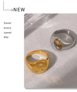 Close-up of gold and silver signet rings with three star-set diamonds on beige surface