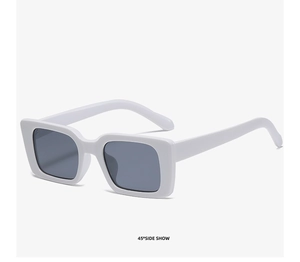 Detail view of white square sunglasses with deep grey lenses and thick fashion frames