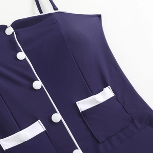 Detailed view of navy swimsuit with white piping, decorative buttons, and pocket flaps