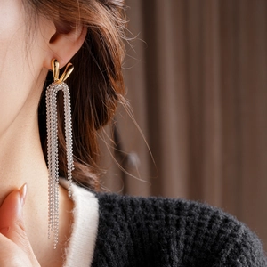 Detailed view of long beaded tassel earrings with gold water drop hoops on a model