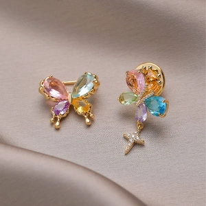 Elegant butterfly brooches with colorful crystals and star charms on champagne silk background