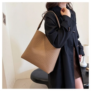 Detail of light brown woven faux leather tote bag on model in a stylish long coat