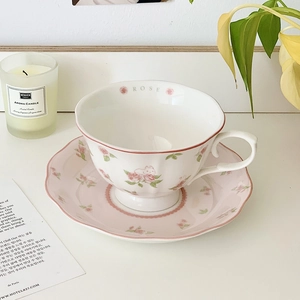 Detail of pink ceramic coffee cup and saucer with rose and bunny illustrations