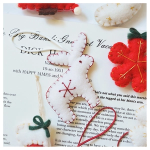 Detail of handmade wool felt Christmas ornaments with red and white hand-stitched seams