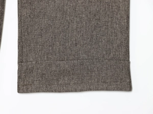 Close-up of brown herringbone trousers showing detailed woven texture and stitching