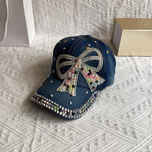 Detailed view of colorful rhinestone bow and silver rivets on dark blue denim baseball cap
