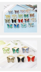 Multiple crystal butterfly rings in various colors with golden metal bands on fabric