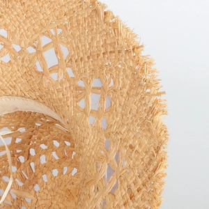Close-up of handmade hollow straw hat featuring intricate crochet texture and frayed edges
