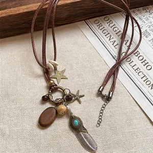 Detail of ethnic feather pendant necklace with wooden beads and turquoise on linen cloth