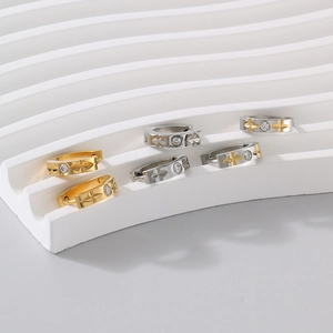 Detailed view of C-shaped earrings with embossed stars and set zircons on stone steps