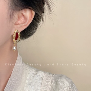 Close-up of French vintage gold earrings with red stones and elegant hanging pearls